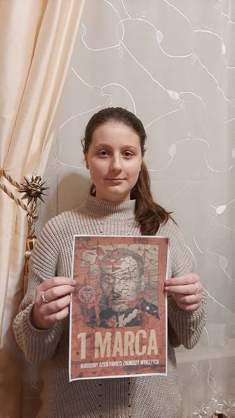 Uczennica prezentująca plakat poświęcony Narodowemu Dniu Pamięci Żołnięrzy Wyklętych.