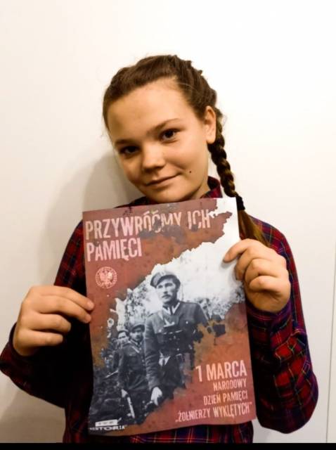 Uczennica prezentująca plakat poświęcony Żołnierzom Wyklętym.