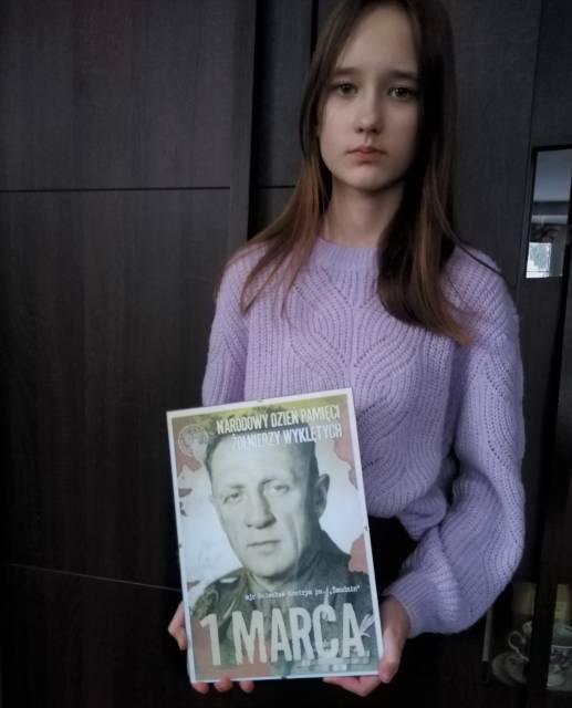 Uczennica prezentująca plakat poświęcony majorowi Bolesławowi Kontrymowi ps. "Żmudzin".