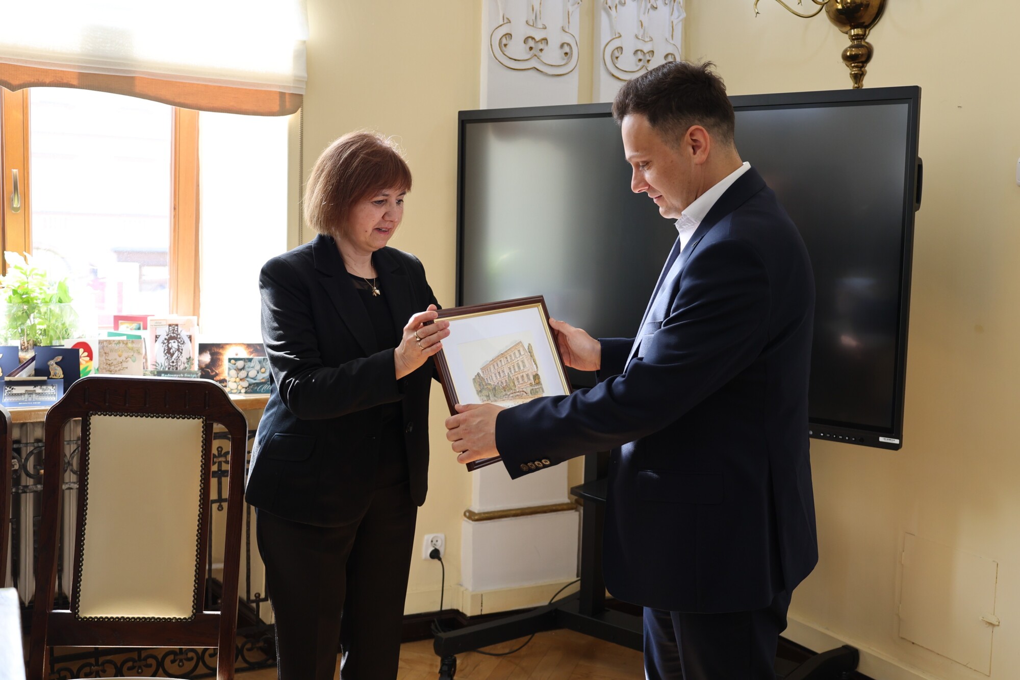 Magdalena Sało, w&nbsp;imieniu grupy, przekazuje Burmistrzowi pamiątkowy obraz.