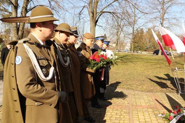 Delegacja służb mundurowych składa kwiaty pod pomnikiem