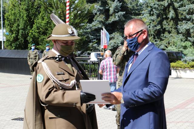 Zastępca burmistrza Wiesław Pirożek składa na ręce dowódcy ppłk. Januszowi Niedźwiedziowi list gratulacyjny