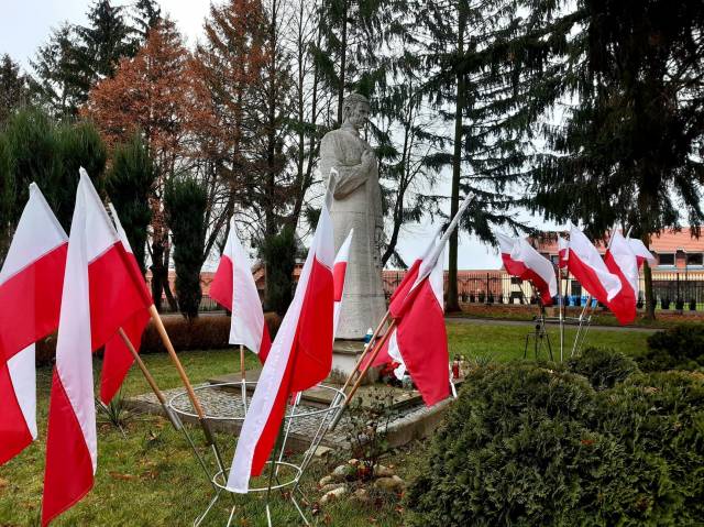 Pomnik bł. ks. Jerzego Popiełuszki oraz powiewające biało-czerwone flagi