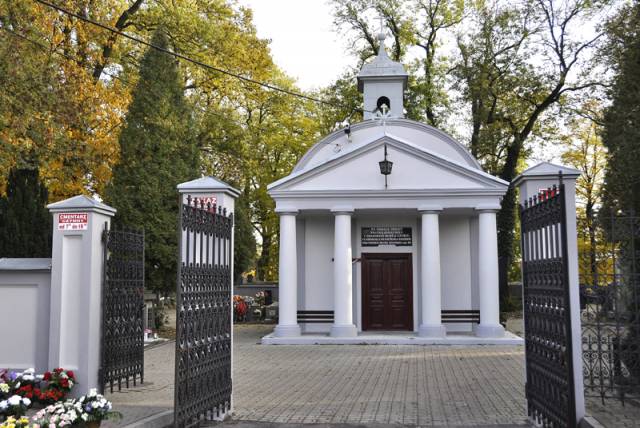 Widok na kaplicę cmentarną przez otwartą bramę.