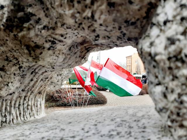 Fragment pomnika przyjaźni polsko-węgierskiej z flagami węgierskimi i polskimi w tle 